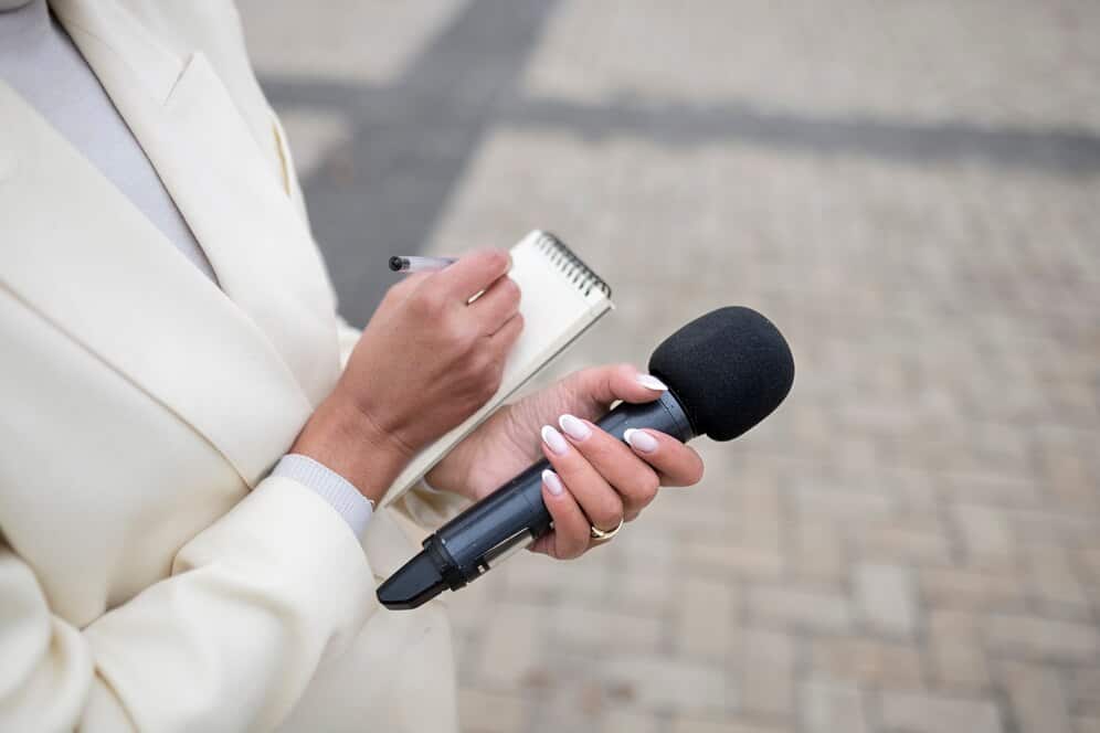 Female holding a mic and a notebook
